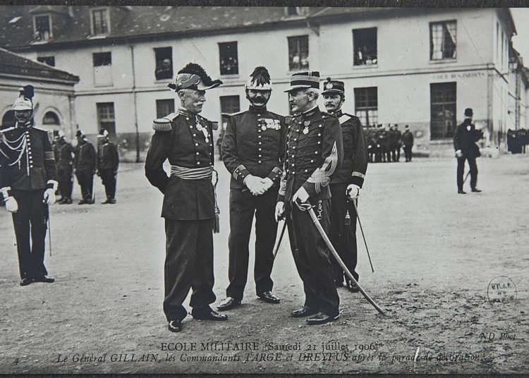 Alfred Dreyfus (ici avec le général Gillain et le commandant Targe) dans la petite cour des jardins de l’École militaire, le 21 juillet 1906. Ce jour-là, Dreyfus, réintégré dans l’armée, est décoré de la Légion d’honneur (Photographie de Charles Chusseau-Flaviens éditée en carte postale).