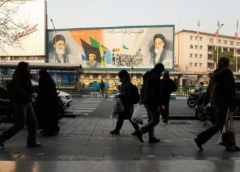 Des passants devant une fresque murale représentant le fondateur de la révolution iranienne, l'ayatollah Khomeini, des membres de la milice paramilitaire Bassidj et le guide suprême, l'ayatollah Ali Khamenei, rue Enqelab-e-Eslami (Révolution islamique) à Téhéran, le 25 janvier 2026 (Photo AP/Vahid Salemi)